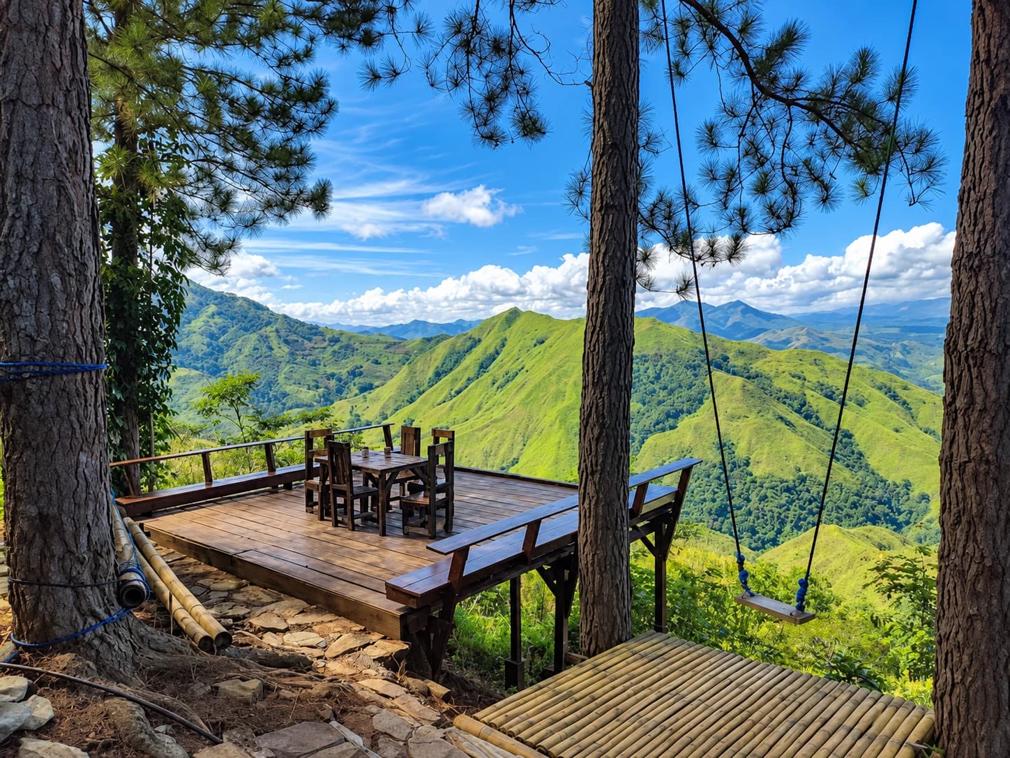 A pine-framed wooden viewing deck and rope swing overlooking green mountain ridges at RotyPeaks