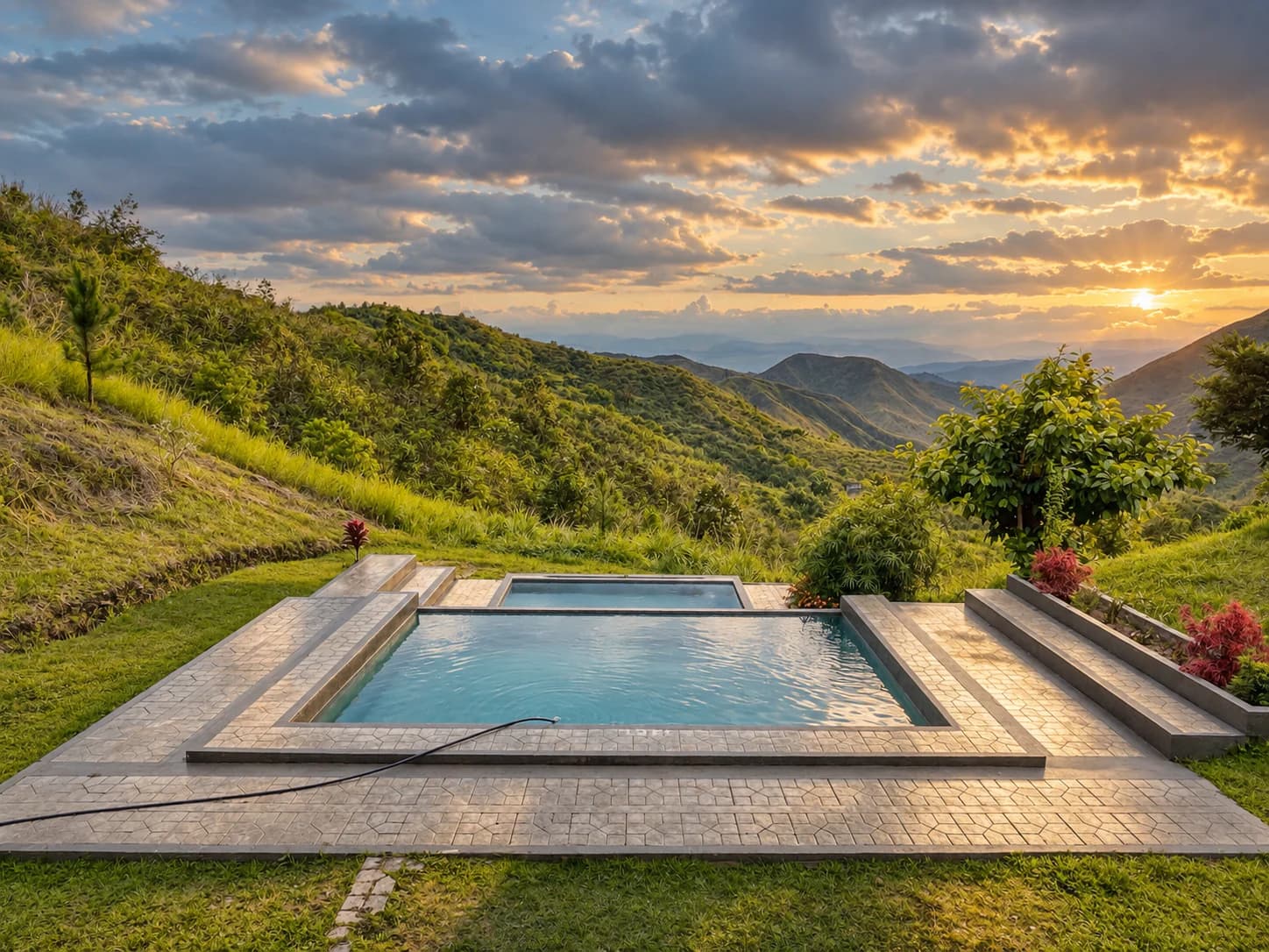 The swimming pool on the lawn beside Barkadahan Cottage Uno at sunset, with green ridges and the valley beyond