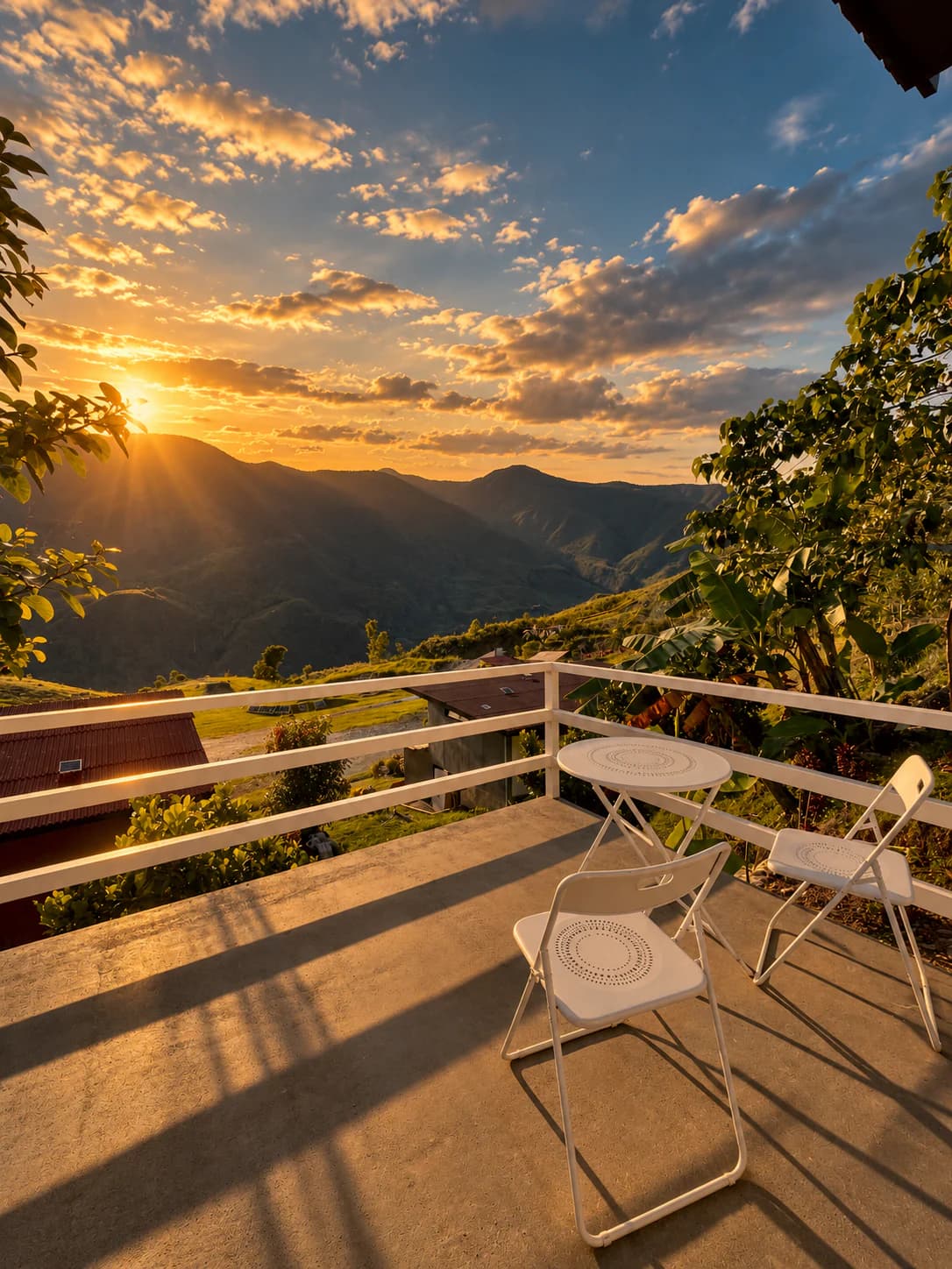 The private balcony of the Couple Cottage at sunset, two chairs and a small table facing the mountains