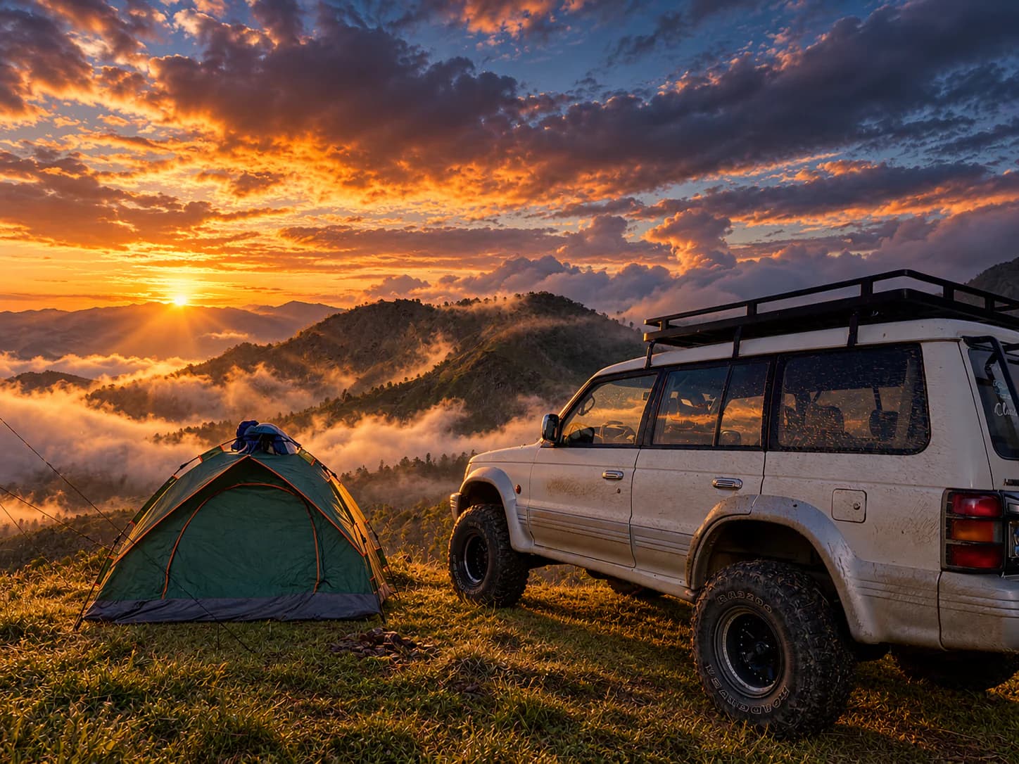 A white SUV parked on the grass beside a tent at sunrise, above a valley filled with cloud